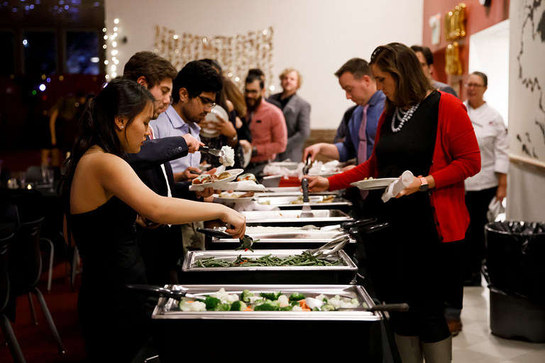 Students in a buffet line fill up reusable plates at the Holly and Ivy Dance at McNutt Quad