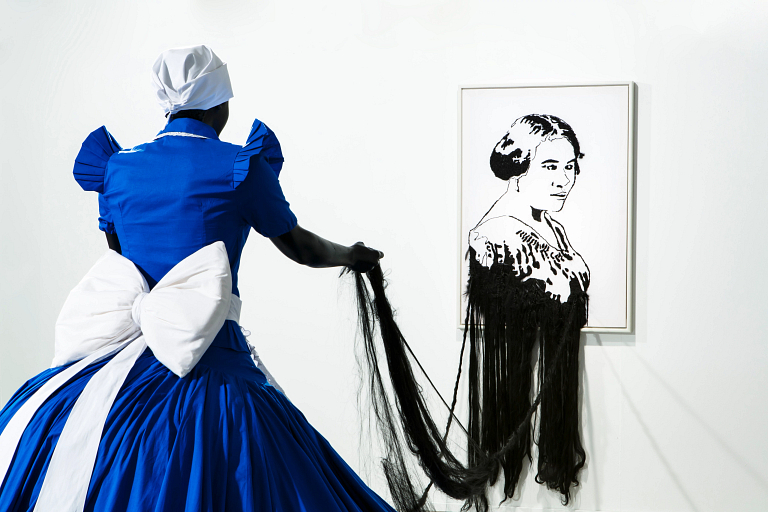 Woman in blue and white holding fabric with picture of Madam C.J. Walker