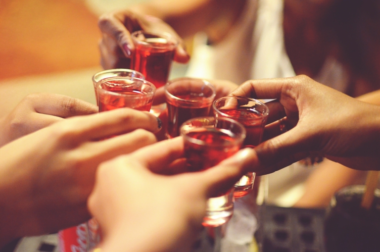 Hands holding shot glasses filled with alcohol