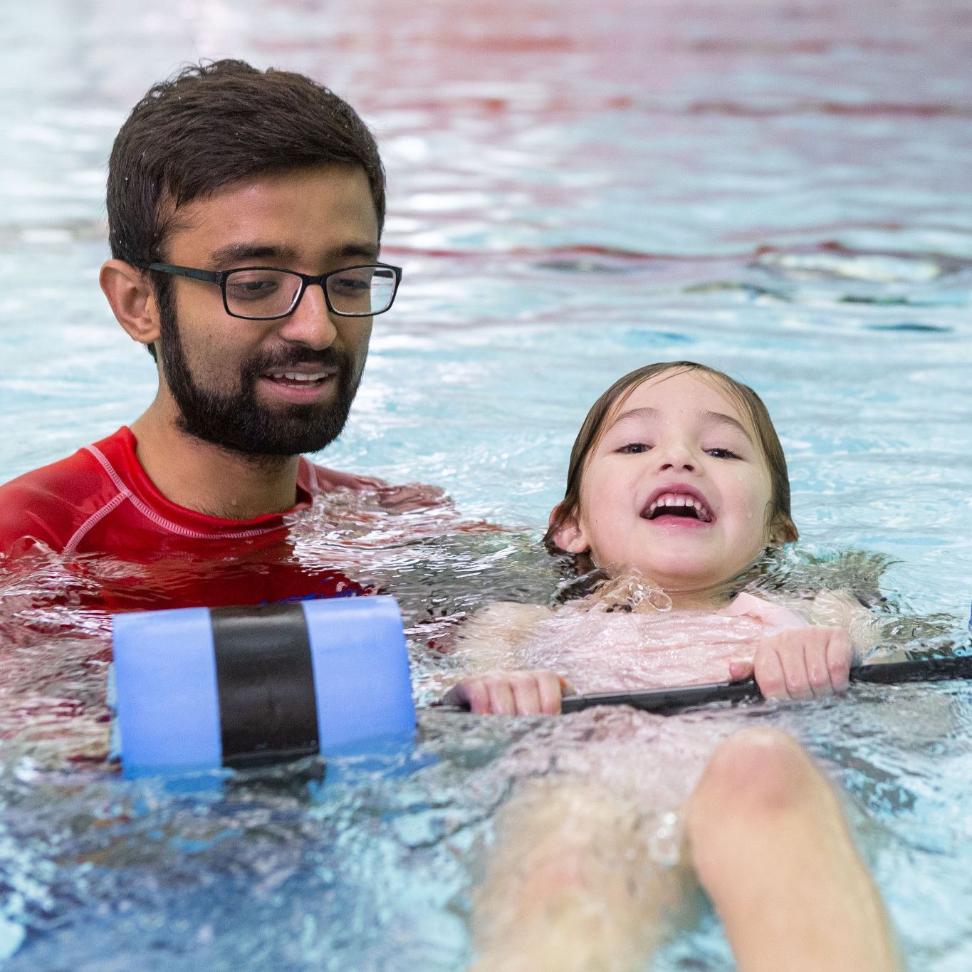 A swim student receives instruction using a floating device