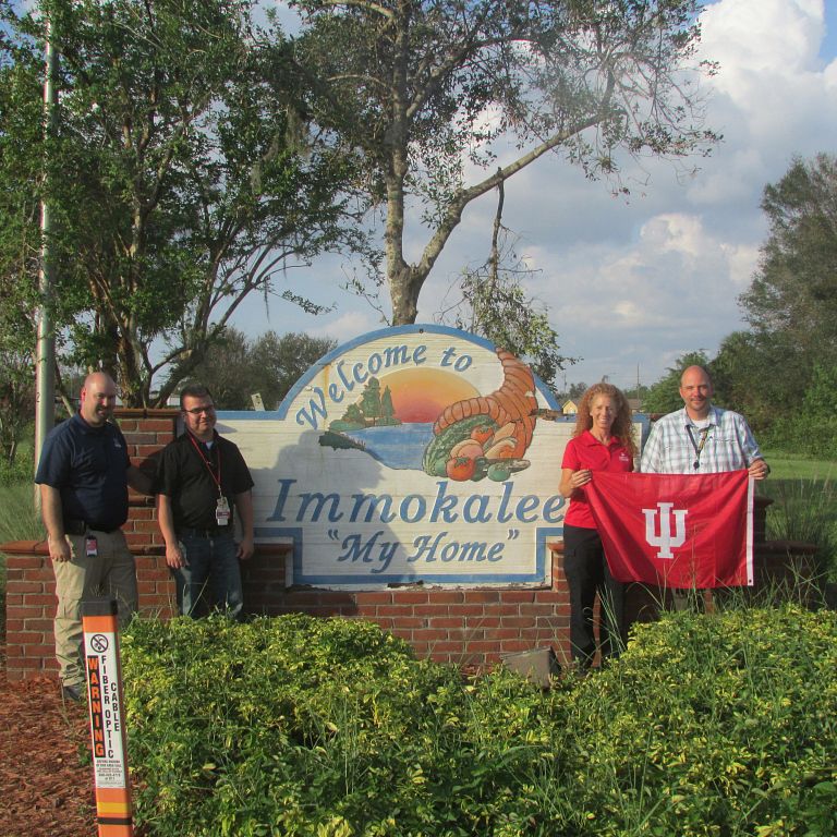 The IU emergency management team hold the IU flag next to a Florida sign