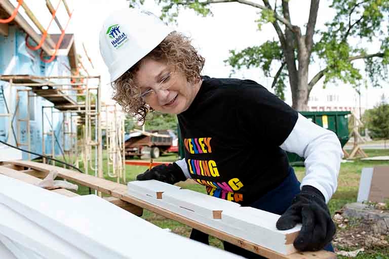 Idalene Kesner is moving pieces of wood on a construction site