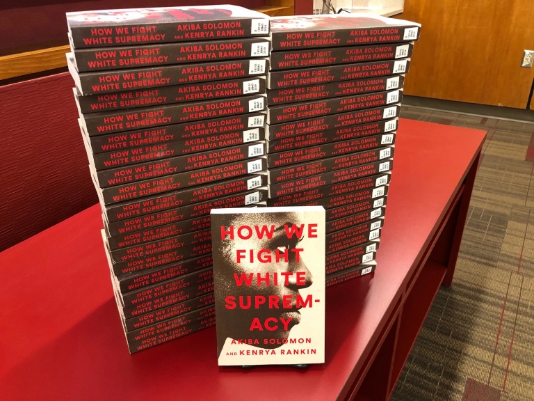 Copies of the book "How We Fight White Supremacy" are stacked on a table.