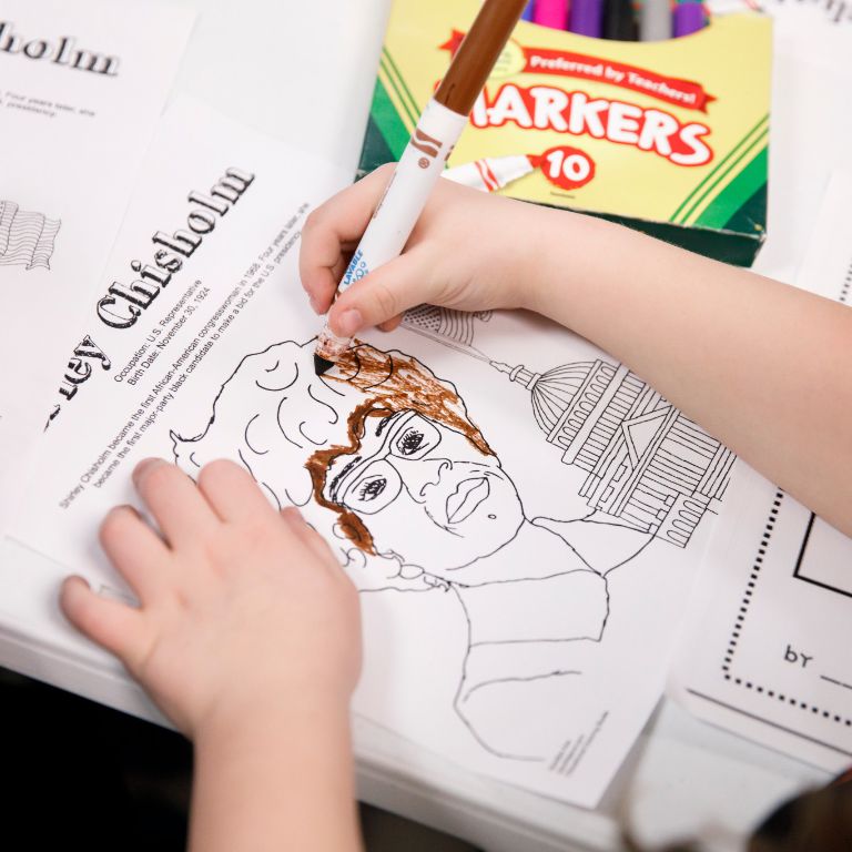 A child colors a picture of Shirley Chisholm