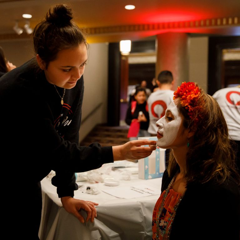 A student paints another student's face