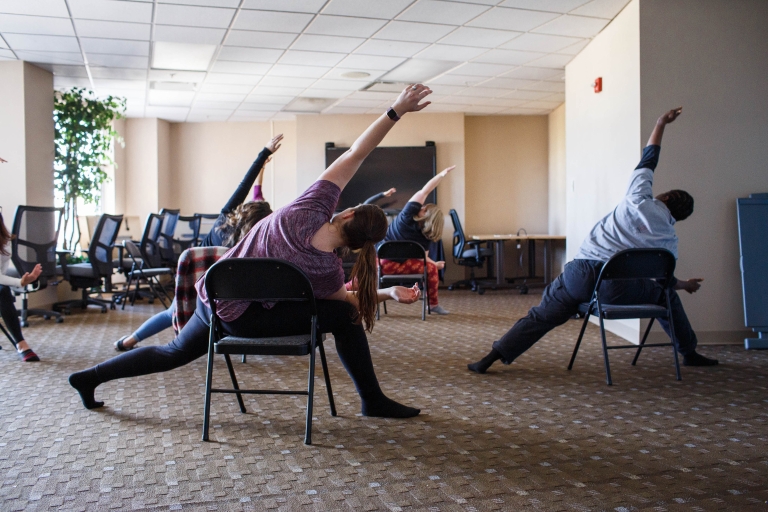 Participants sit in chairs and stretch during a chair yoga class