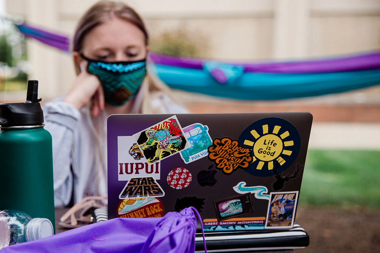 IUPUI student studying at a laptop covered in stickers