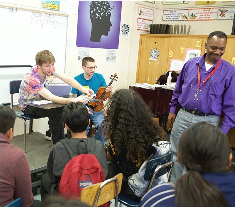 Members of The String Bank show musical instruments to students.