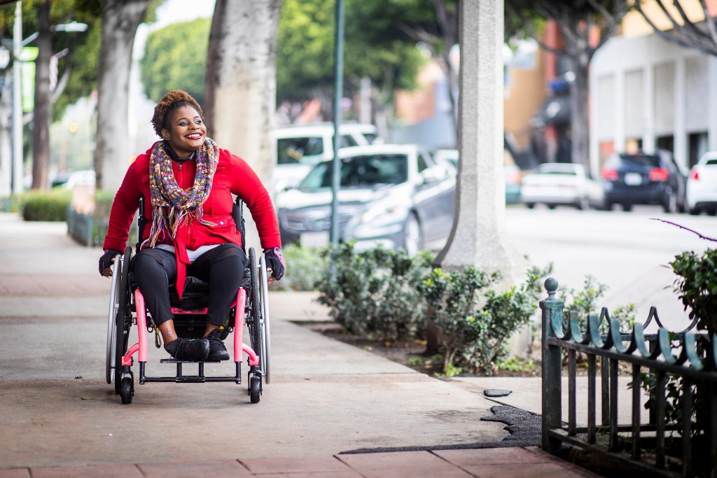 A woman uses a wheelchair on a city sidewalk