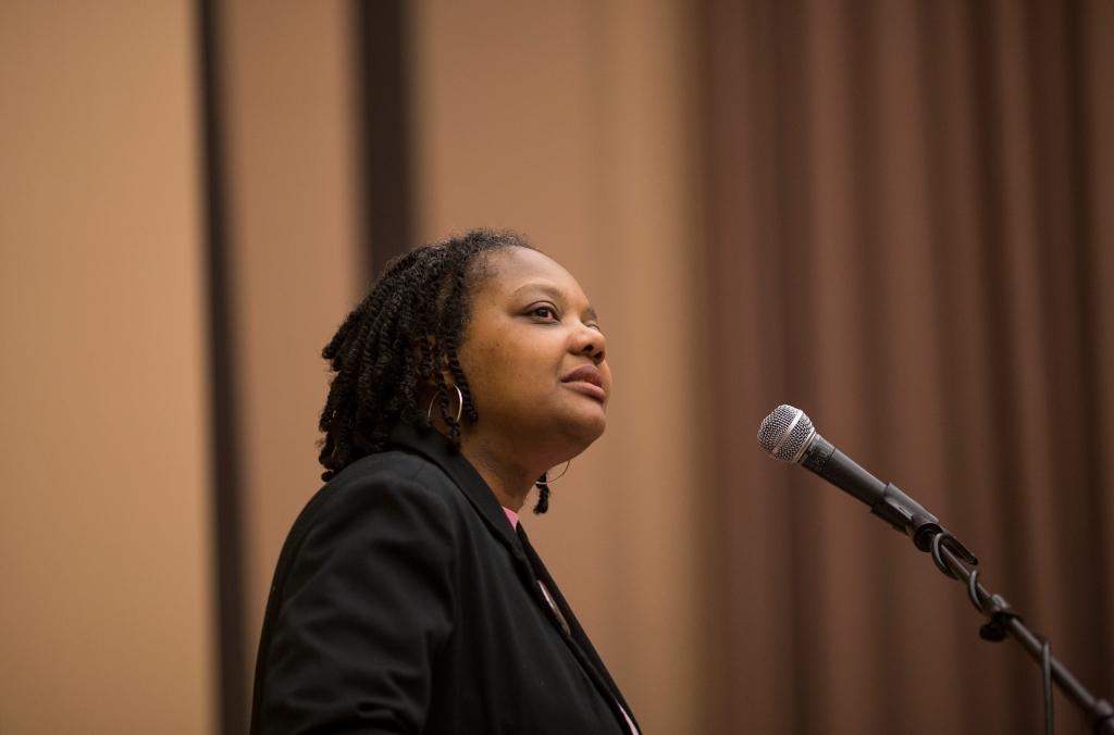 Stephanie Power-Carter looks on at a podium in front of a microphone