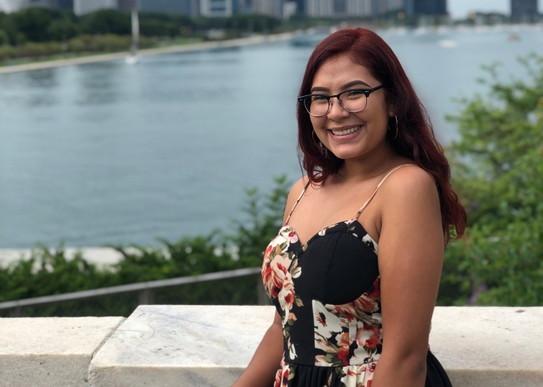 IUPUI student Alexa Soto smiles and poses for a photo in front of a city skyline.