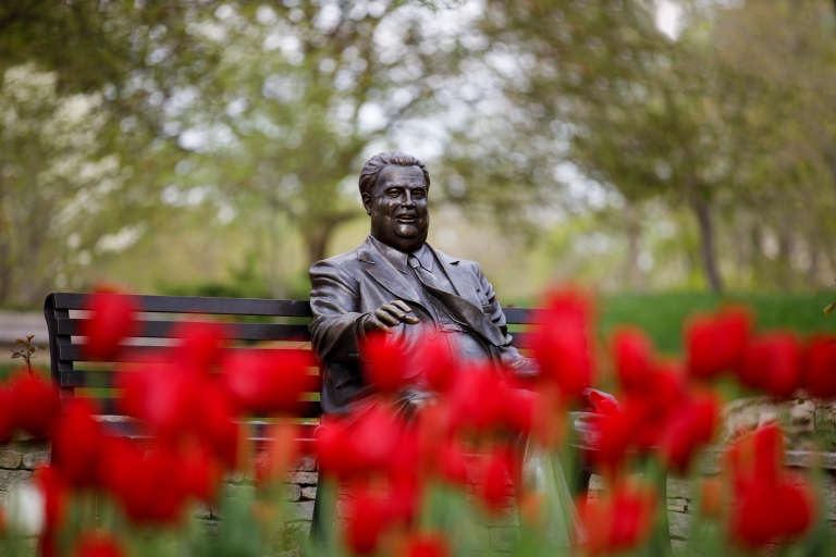 The Herman B Wells statue with a blur of red tulips in the foreground