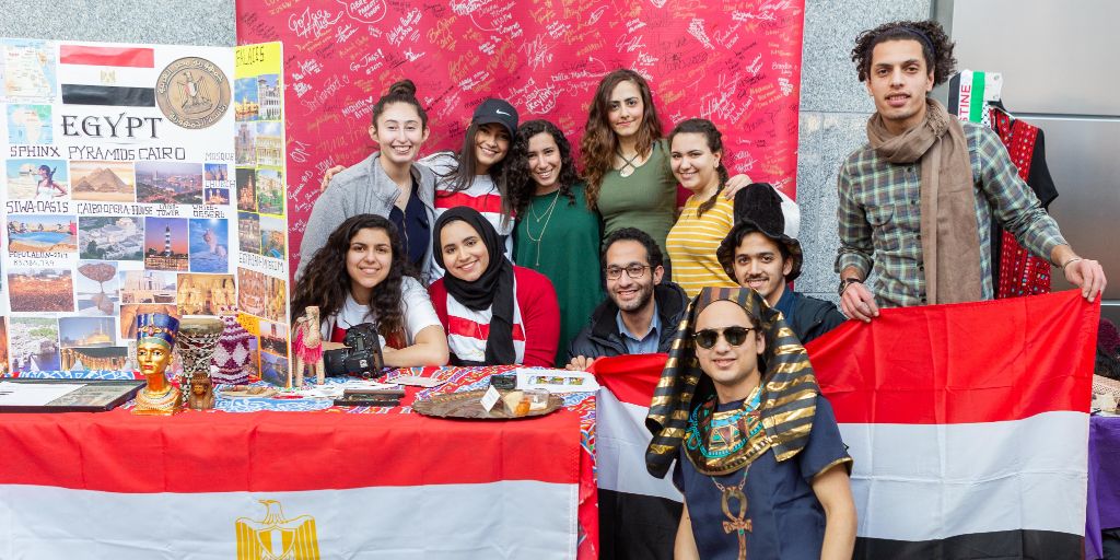 A group of students posing for a picture near the Egypt booth at the International Festival