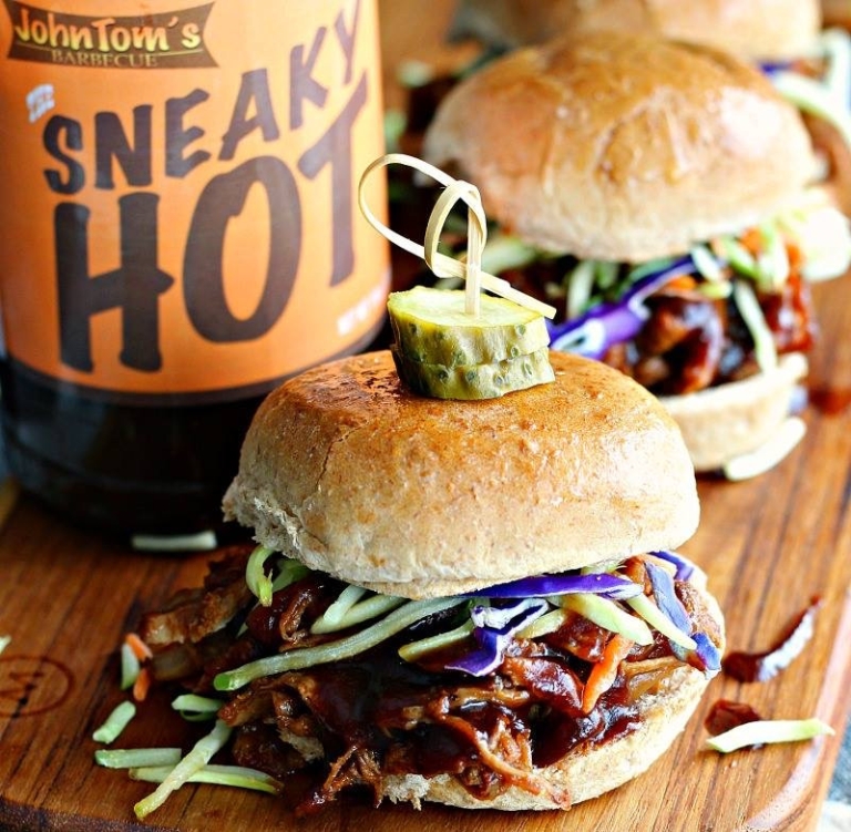 Close-up of a barbecue sandwich and a bottle of JohnTom's Barbecue sauce.