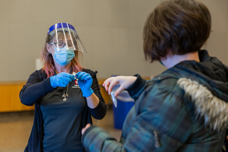 A health care worker administers a COVID-19 test to a woman