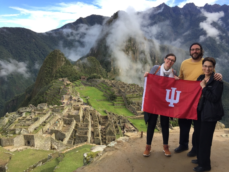 Janice poses with her two children and an IU flag with Machu Picchu in the background 
