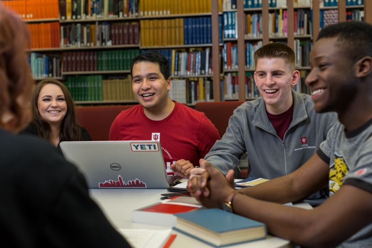 Four students study together in a library.