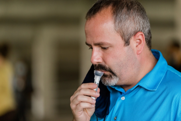 A man takes a COVID-19 mitigation test by spitting into a tube