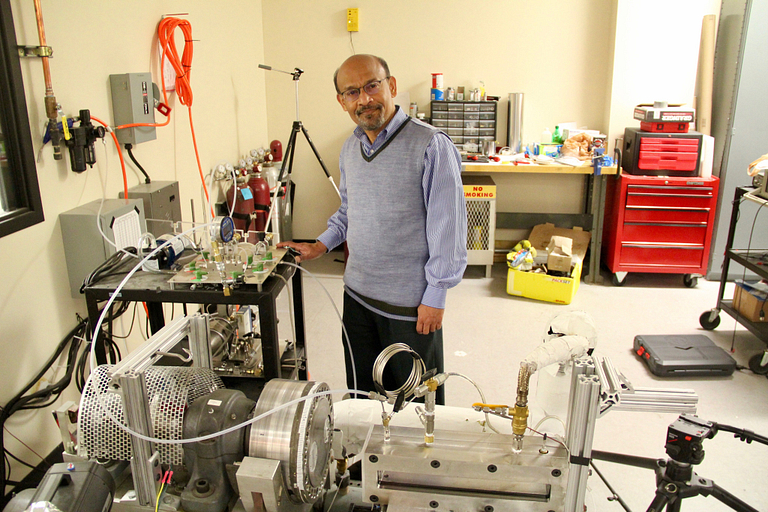 Nalim stands with an engine rig in his lab.