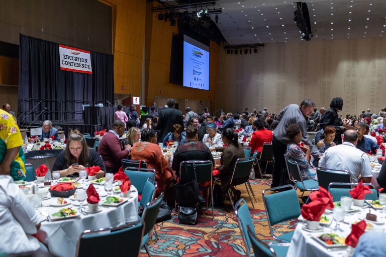 A large convention room filled with tables and people for a conference