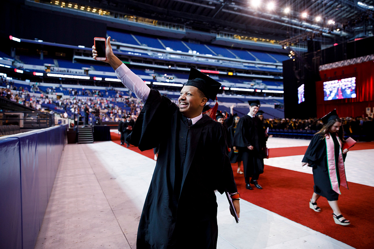 A graduate gives a thumbs-up after receiving his degree.