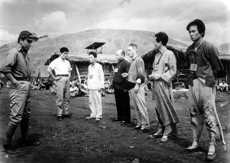 Several men stand outside in a black-and-white scene from 'Human Condition'