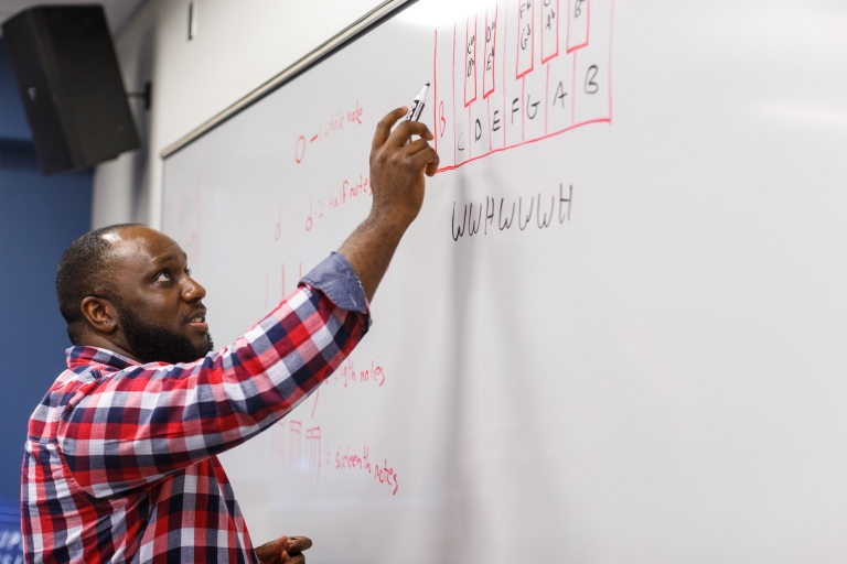 Alan Tyson II transcribes the mathematics behind the music on a board.