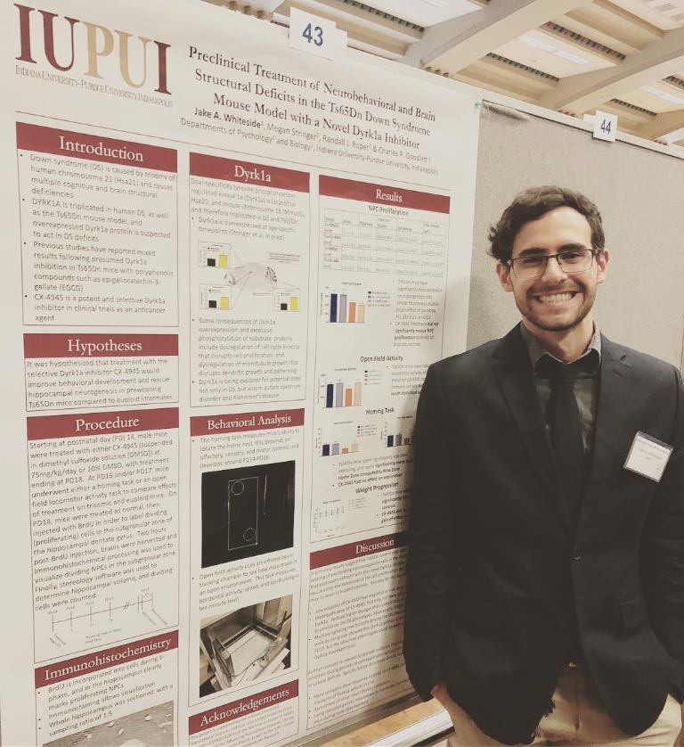 Jake Whiteside stands in front of a large poster explaining scientific research.