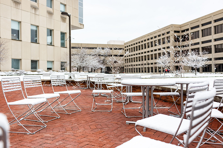 Seating in front of the library is covered in snow.