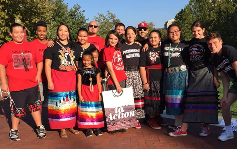 Participants in Indigenous Peoples' Day stand in front of First Nations building.