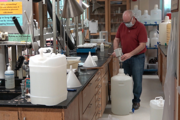 A man stands in a lab making hand sanitizer