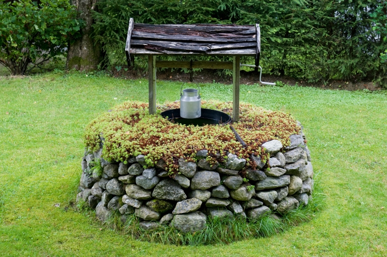 An outdoor well in the middle of green grass