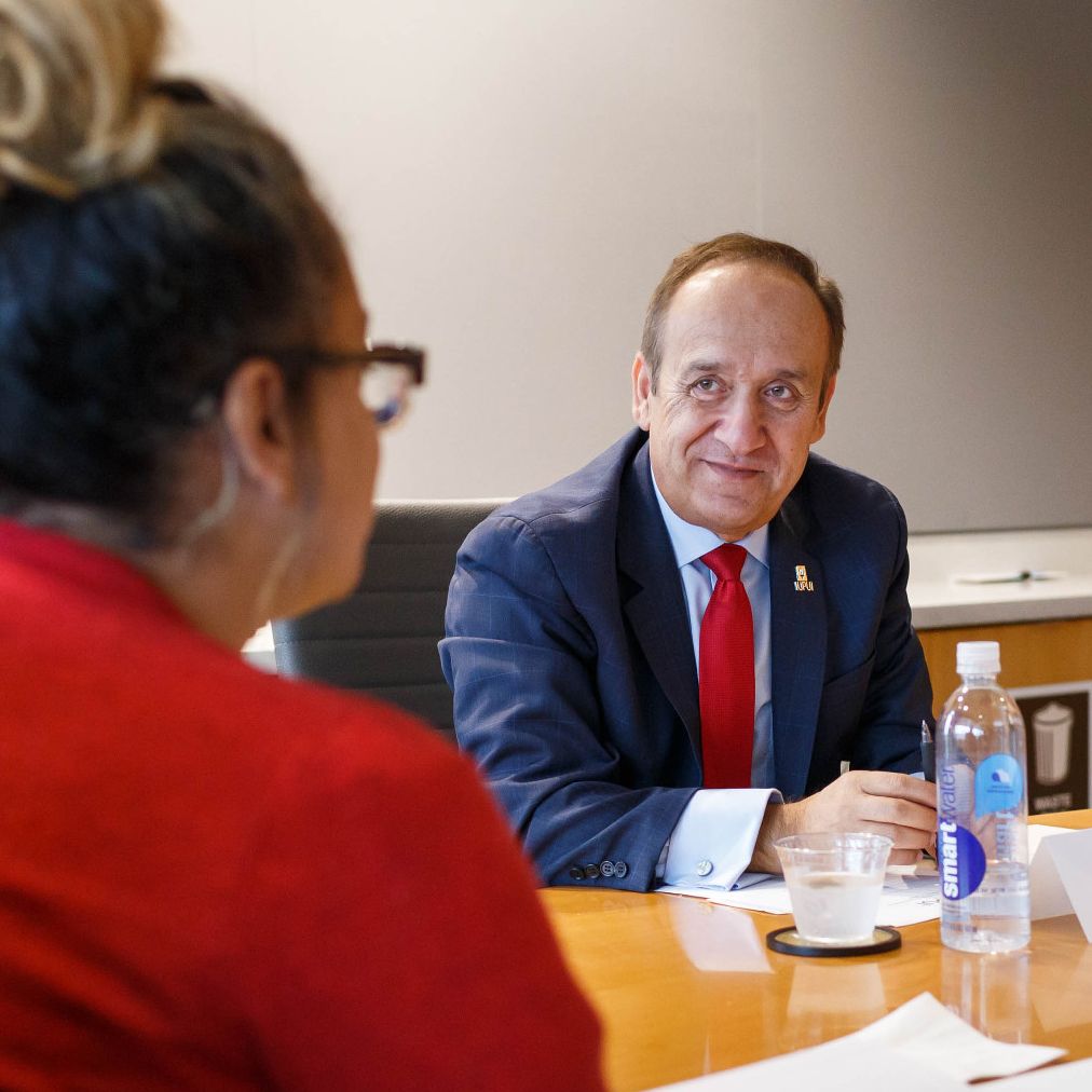 Chancellor Paydar listens and smiles at Saliena Balos as she gives updates during a meeting.