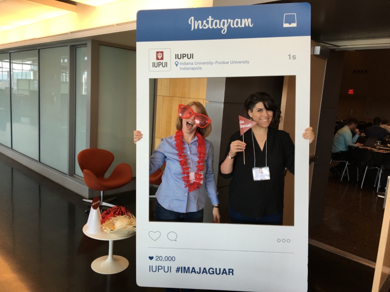 Two women pose in front of an Instagram cutout