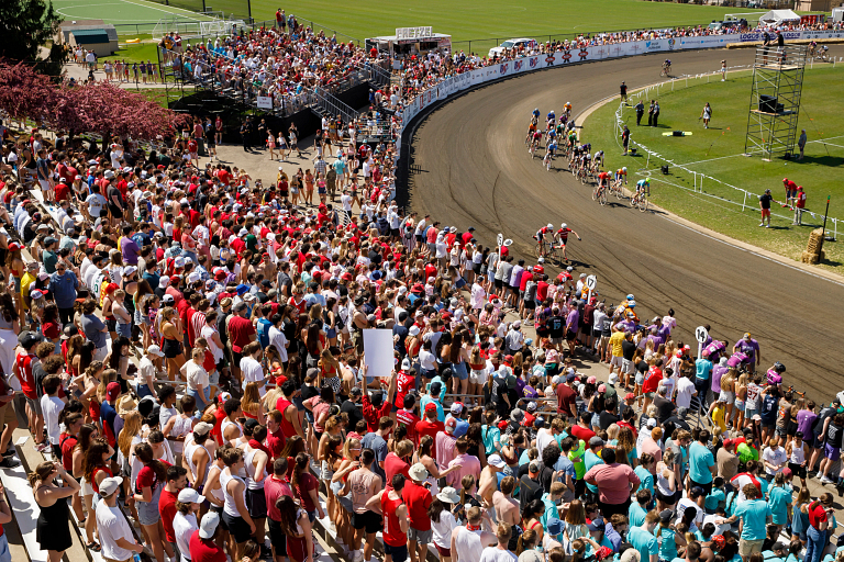 Aerial view of hundreds of fans in the stands watching cyclists race around a track.