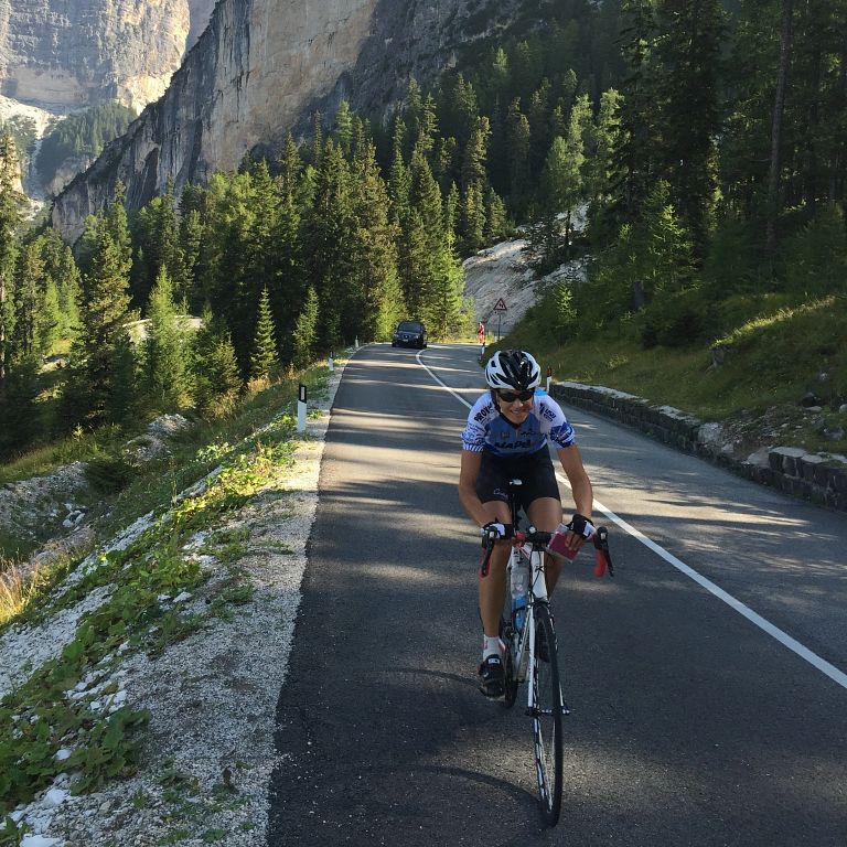 A woman in a cycling helmet rides a bike on a mountain road.