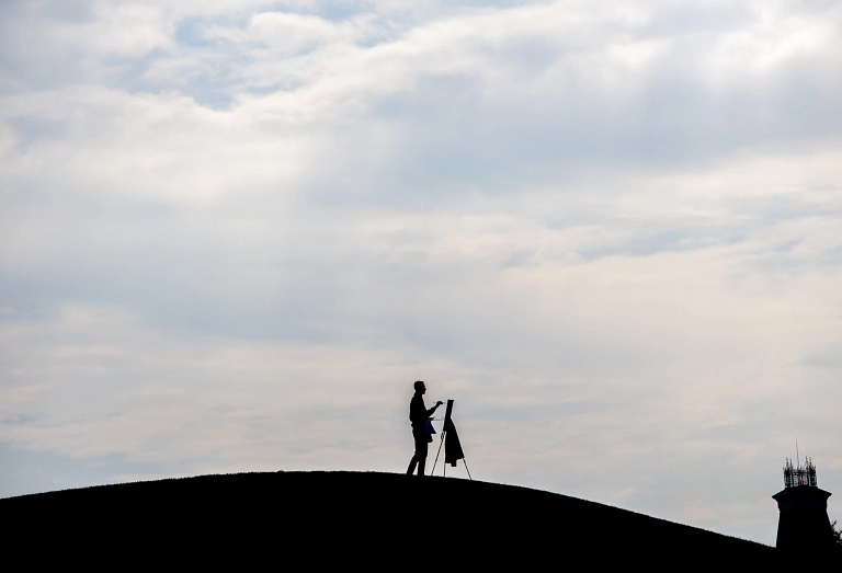 A student paints on a hill at Mill Race Park 