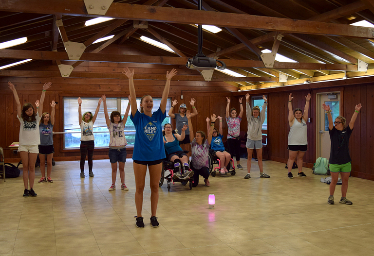 Camp Riley dancers raise their hands above their heads