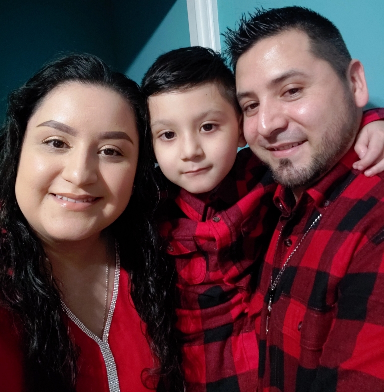 a woman poses for a picture with her son and husband