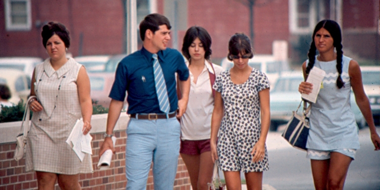 A man and four women walk on IUPUI's campus in the 1970s.