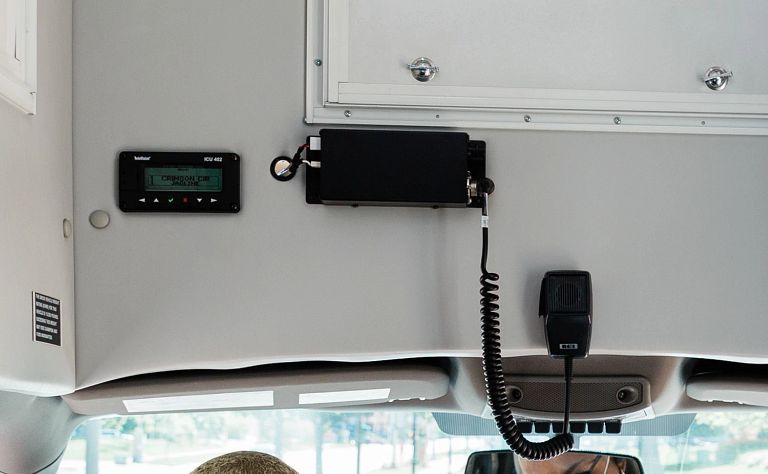 Interior of a bus with a hand sanitizer dispenser and a driver wearing a mask