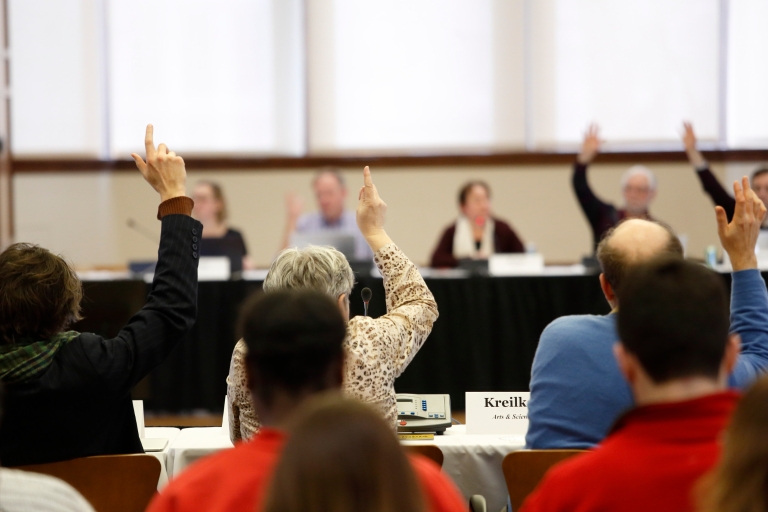 Bloomington Faculty Council members raise their hands at a meeting
