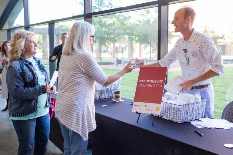 A person hands out naloxone samples at a table at the IU Grand Challenge naloxone training in 2018.