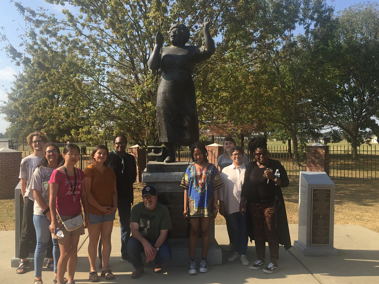 A group of people stand in a statue in a park