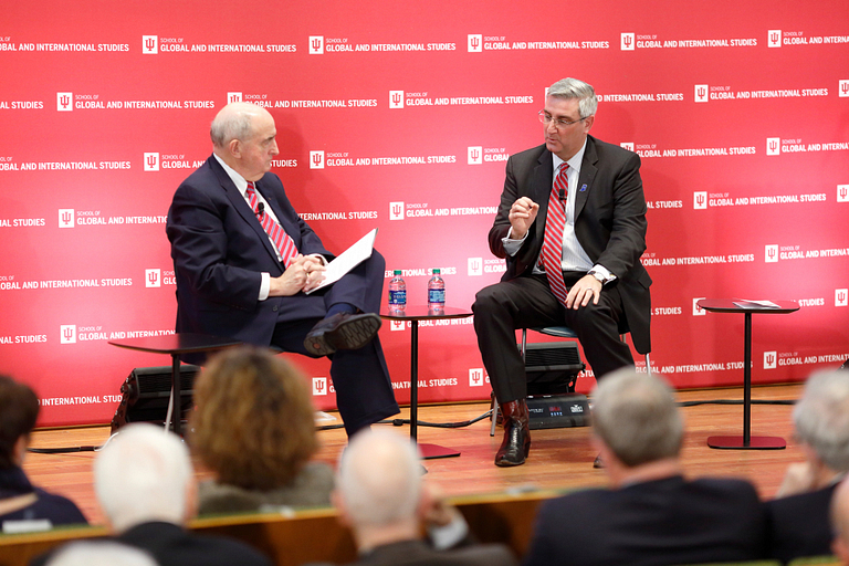 IU President Michael A. McRobbie, left, sits on stage with Indiana Gov. Eric Holcomb.