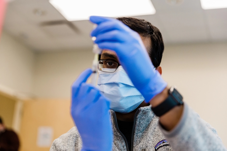 a medical student practices giving a vaccine