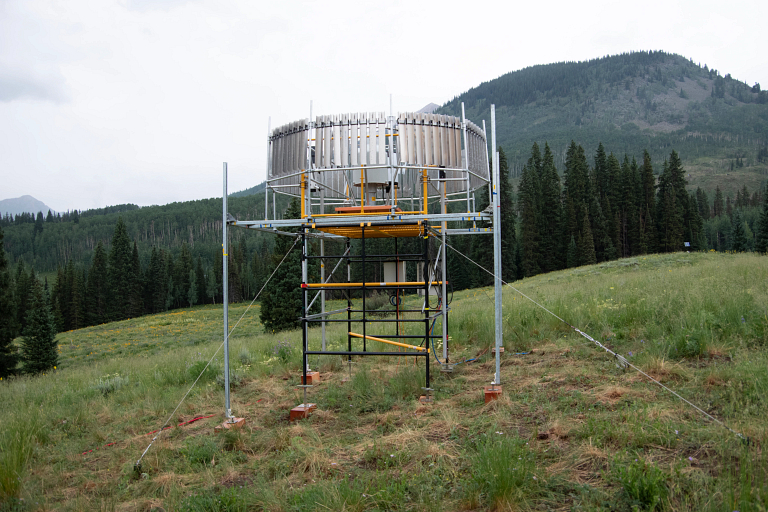 An instrument to collect weather data sits in a field with a mountain in the background