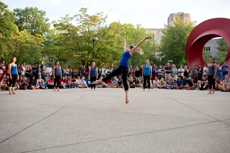 A dancer jumps in front of the Eskenazi Museum of Art at IU