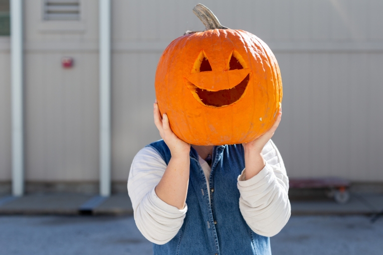 Student holds carved pumpkin.