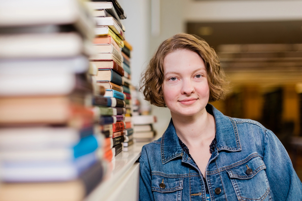 IUPUI student Eden Rea- Hedrick standing near a shelf of stacked books.